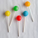 A group of lollipops on white paper sticks with different colors on them.
