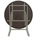 A Flash Furniture round brown rattan plastic folding table with metal legs.