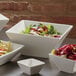 An American Metalcraft white porcelain square bowl filled with salad.