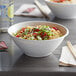 A white Eco-Products compostable noodle bowl filled with noodles and vegetables with chopsticks.