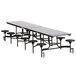 A long black rectangular cafeteria table with metal legs and round black stools.