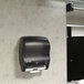 A black San Jamar Hybrid Classic paper towel dispenser on a wall above a sink.