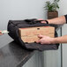 A person handing a Cambro Premium Pizza Delivery GoBag to someone holding a pizza box.