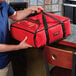 A man holding a red Cambro pizza delivery bag.