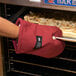A person using a San Jamar Cool Touch Flame oven mitt to open an oven.