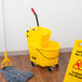 A yellow Rubbermaid WaveBrake mop and bucket set on the floor.