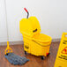 A yellow Rubbermaid mop bucket with wringer on a wood floor.