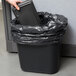 A hand holding a black Continental rectangular trash can.