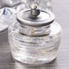 A glass jar with a metal lid filled with clear liquid.