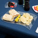 A Fineline clear plastic luncheon plate with a sandwich, chips, and a drink on it.
