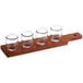 An Acopa mahogany flight paddle with rounded tasting glasses on it.