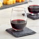 An Acopa stemless wine glass of red wine on a slate coaster.