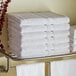 A metal rack with a stack of white Lavex bath towels.