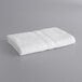A Lavex white cotton/poly bath towel on a gray surface.