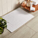 A white Lavex bath mat on a wooden floor.