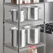 A metal rack with Choice aluminum stock pots and covers on it.