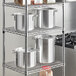 A metal rack with Choice aluminum stock pots and covers on it.