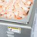 A large countertop container of shrimp.