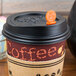 A Royal Paper Stix To Go orange beverage plug and stirrer in a coffee cup with a lid.
