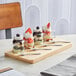 An Acopa wooden flight tray with mini mason jar desserts filled with fruit and whipped cream.