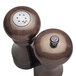 A Chef Specialties burnished copper pepper mill and salt shaker set on a table with silver lids.