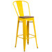 A yellow bar stool with a wooden seat.