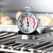 A Comark 2" dial oven thermometer on a grill.