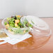 A salad in a Dart clear plastic bowl with a lid.