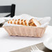 A beige rectangular woven rattan basket filled with sliced bread on a table.