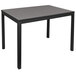 A BFM Seating black metal bolt-down bar height table with a gray synthetic teak top.