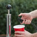 A hand holding a black handle and a red cup attached to a hose.