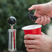 A person using a Backyard Pro party pump to pour beer into a red cup.