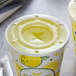 A clear plastic Carnival King cold cup lid with a straw slot on a cup of lemonade