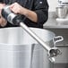 A chef using a Waring stainless steel immersion blender in a large pot.