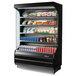 A Turbo Air black refrigerated air curtain merchandiser with food and drinks on shelves inside.