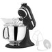 A KitchenAid Artisan mixer in black with a bowl and whisk attachment.