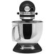 A KitchenAid Artisan Series countertop mixer in black and silver with a handle.