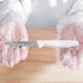 A person in a white coat holding a Dexter-Russell Basics white paring knife in plastic.