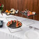 A table with Acopa Slate Chrome Wire risers holding plates of food.