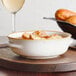 An Acopa Keystone stoneware bowl of French onion soup with bread on a tray.