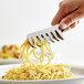 A person using Vollrath stainless steel tongs to serve spaghetti on a plate with a fork.