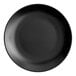 A close up of an Acopa matte black stoneware coupe plate.