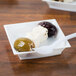 A small square white bowl with olives and cheese on a WNA Comet Petite white square dish.