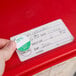 A hand places a Noble Products Friday food labeling sticker on a red box.