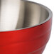 A close up of a Vollrath fire engine red metal serving bowl with a stainless steel handle.