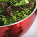 A Fire Engine Red Vollrath beehive serving bowl filled with lettuce and other greens.