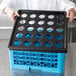 A person using a blue plastic Cambro IceExpress glass filler crate.