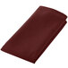 A folded Intedge burgundy cloth napkin.