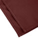 A folded burgundy Intedge cloth napkin.