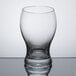 A Stolzle clear tumbler with a small amount of liquid in it.